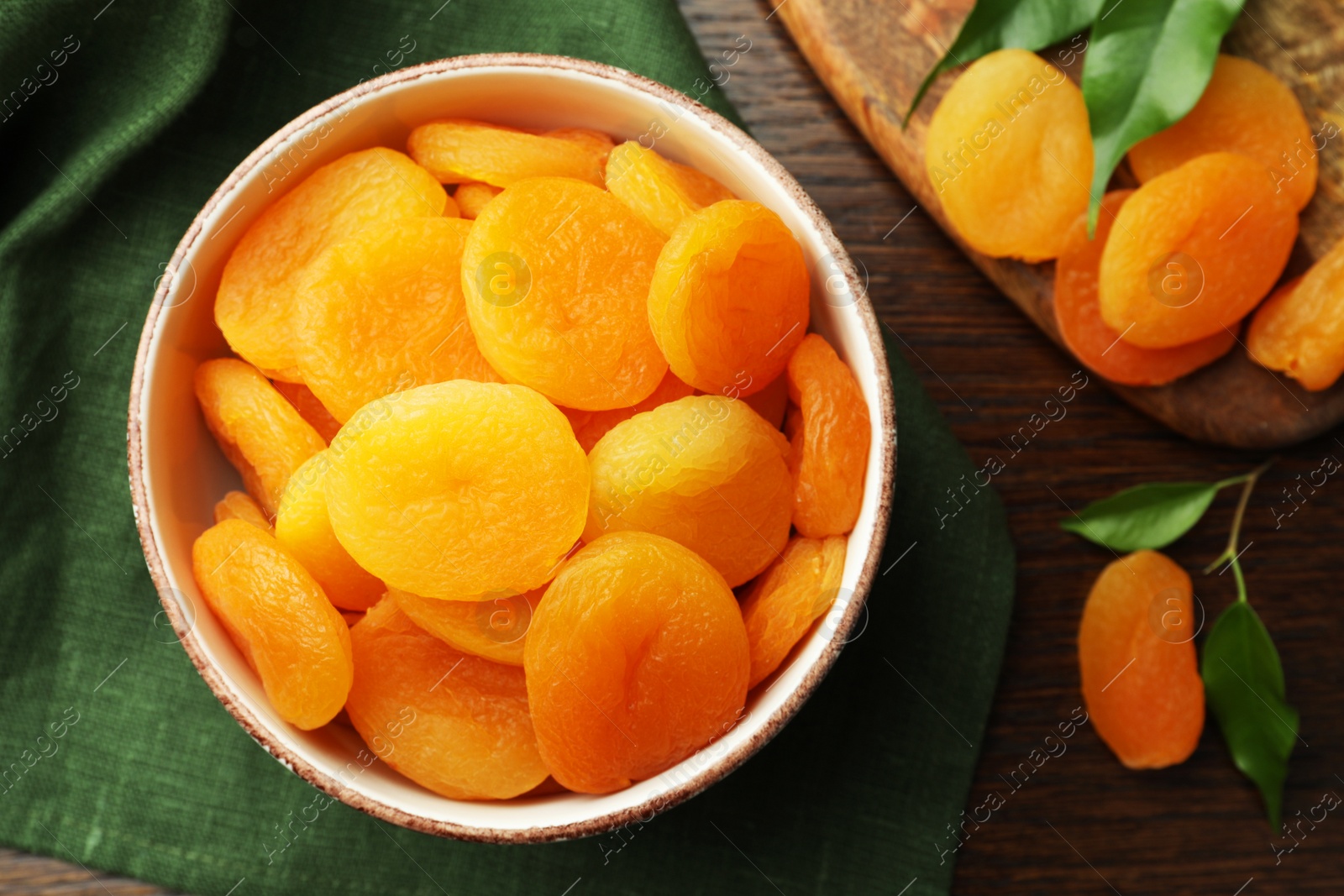 Photo of Bowl of tasty apricots on wooden table, flat lay. Dried fruits