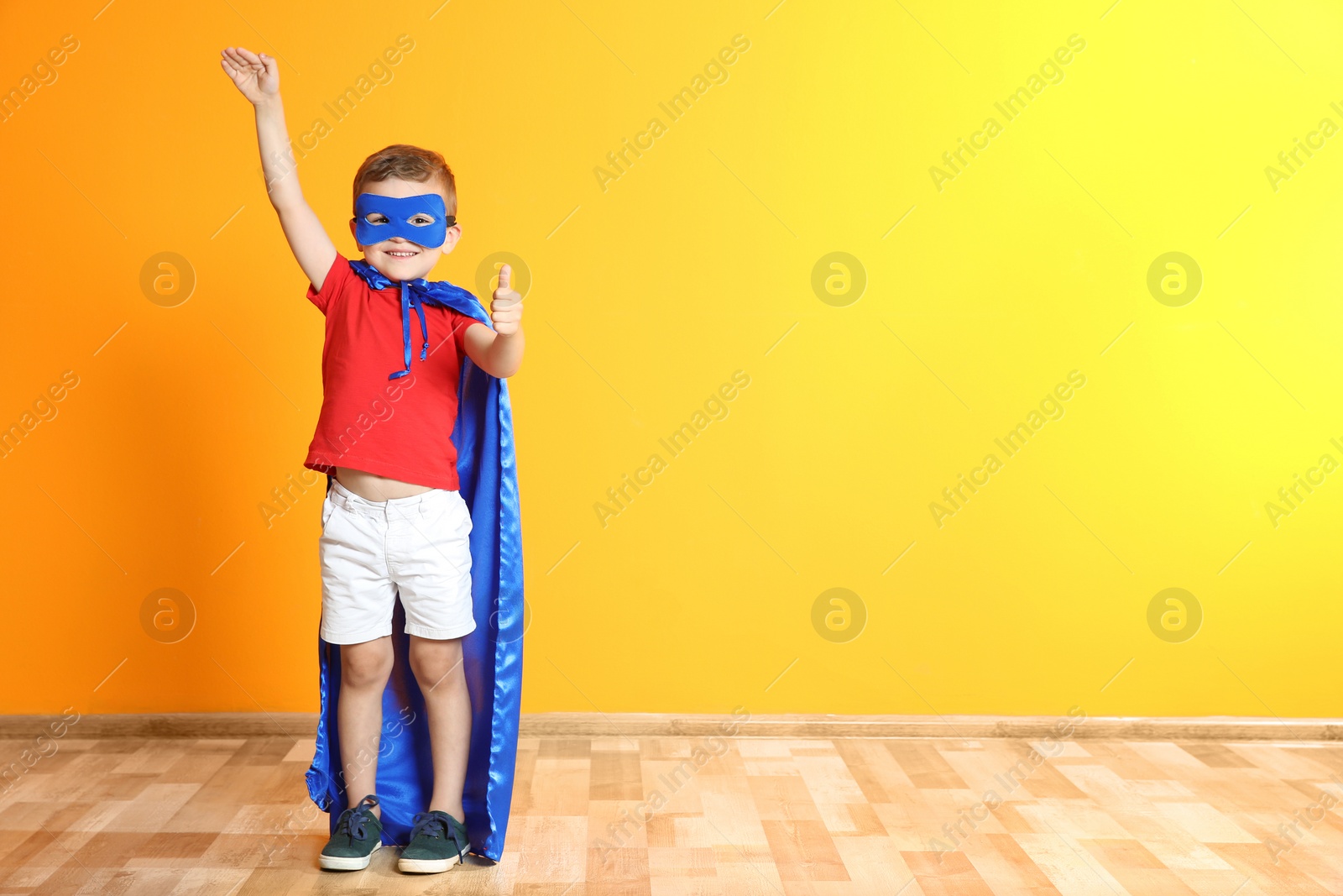 Photo of Adorable little child playing superhero indoors