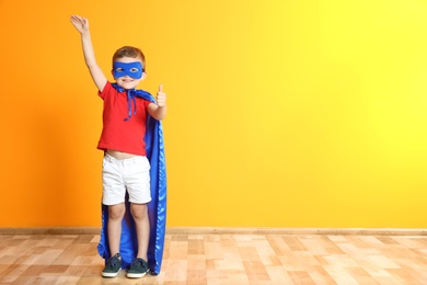 Adorable little child playing superhero indoors