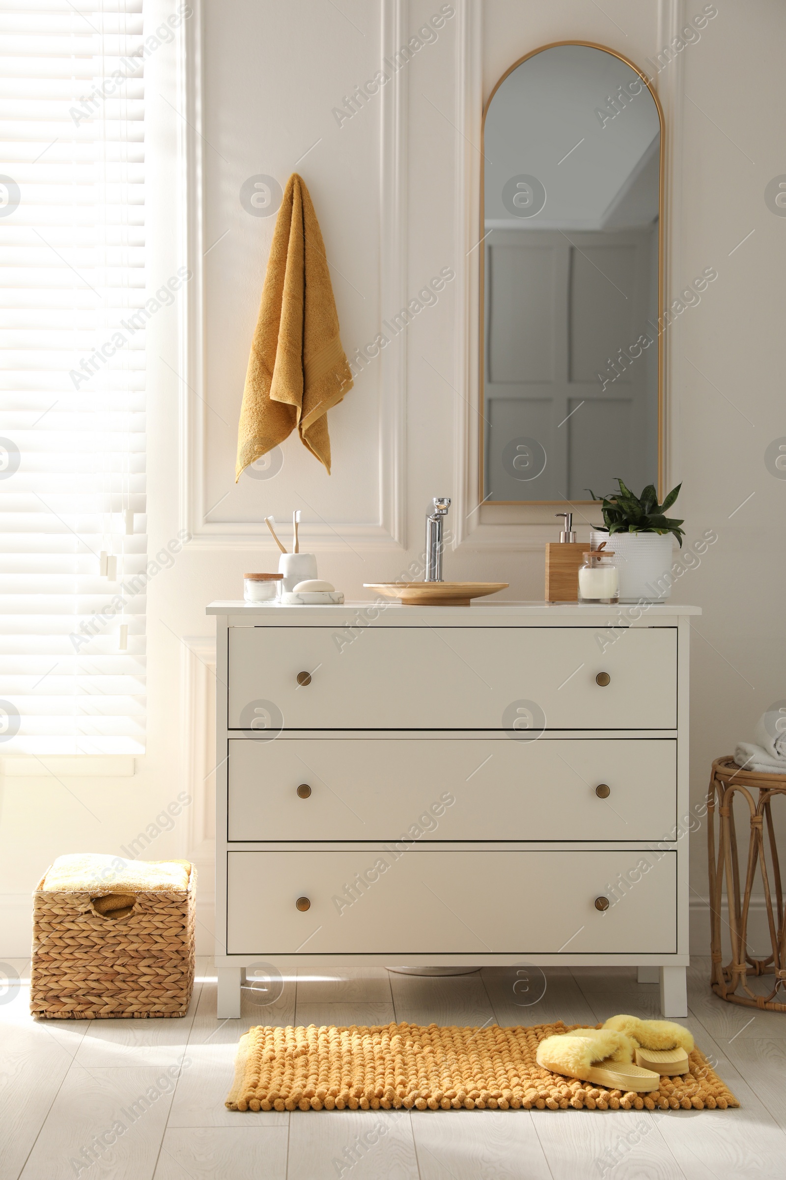 Photo of Stylish orange mat with slippers near chest of drawers in bathroom