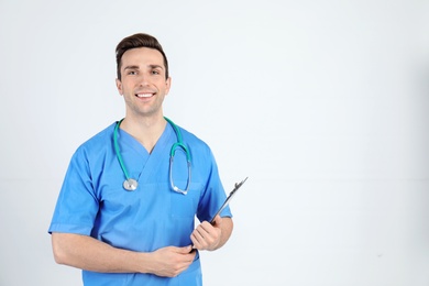 Photo of Portrait of medical assistant with stethoscope and clipboard on light background. Space for text