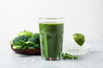 Photo of Delicious green juice and fresh ingredients on grey marble table