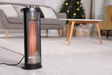 Photo of Modern electric heater on floor at home. Space for text