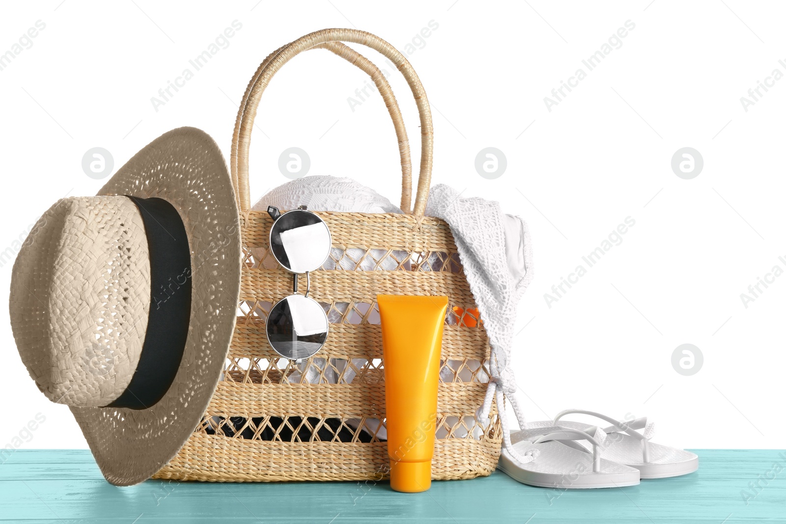 Photo of Set of beach accessories on blue wooden table, white background