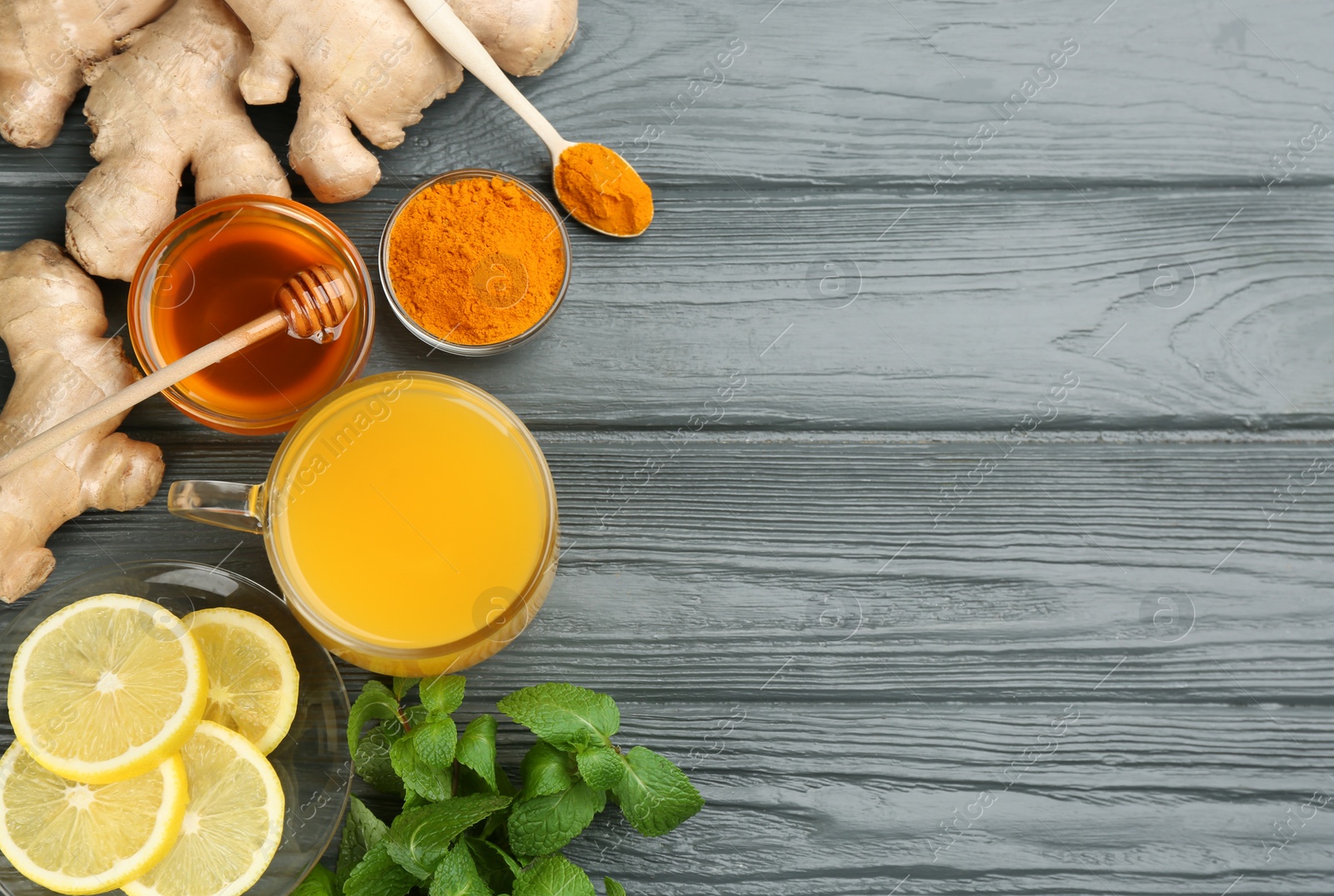 Photo of Flat lay composition with immunity boosting drink and ingredients on grey wooden table. Space for text