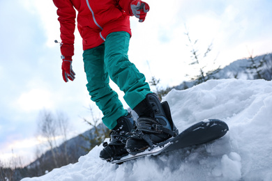 Young snowboarder on snowy hill, closeup. Winter vacation