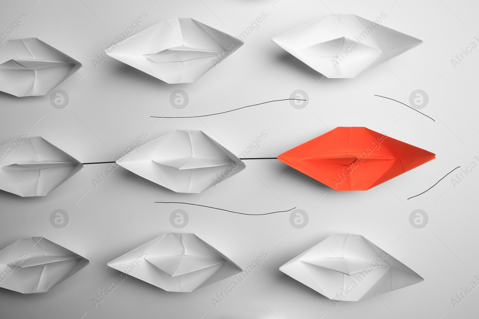 Photo of Group of paper boats following orange one on white background, flat lay. Leadership concept