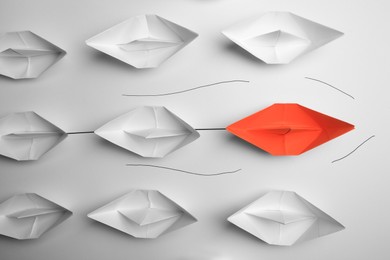 Photo of Group of paper boats following orange one on white background, flat lay. Leadership concept