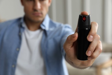 Photo of Man using pepper spray at home, focus on hand