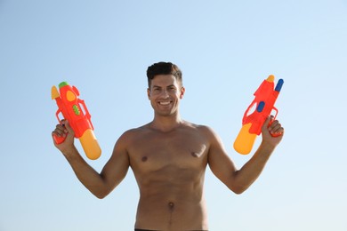 Man with water guns against blue sky