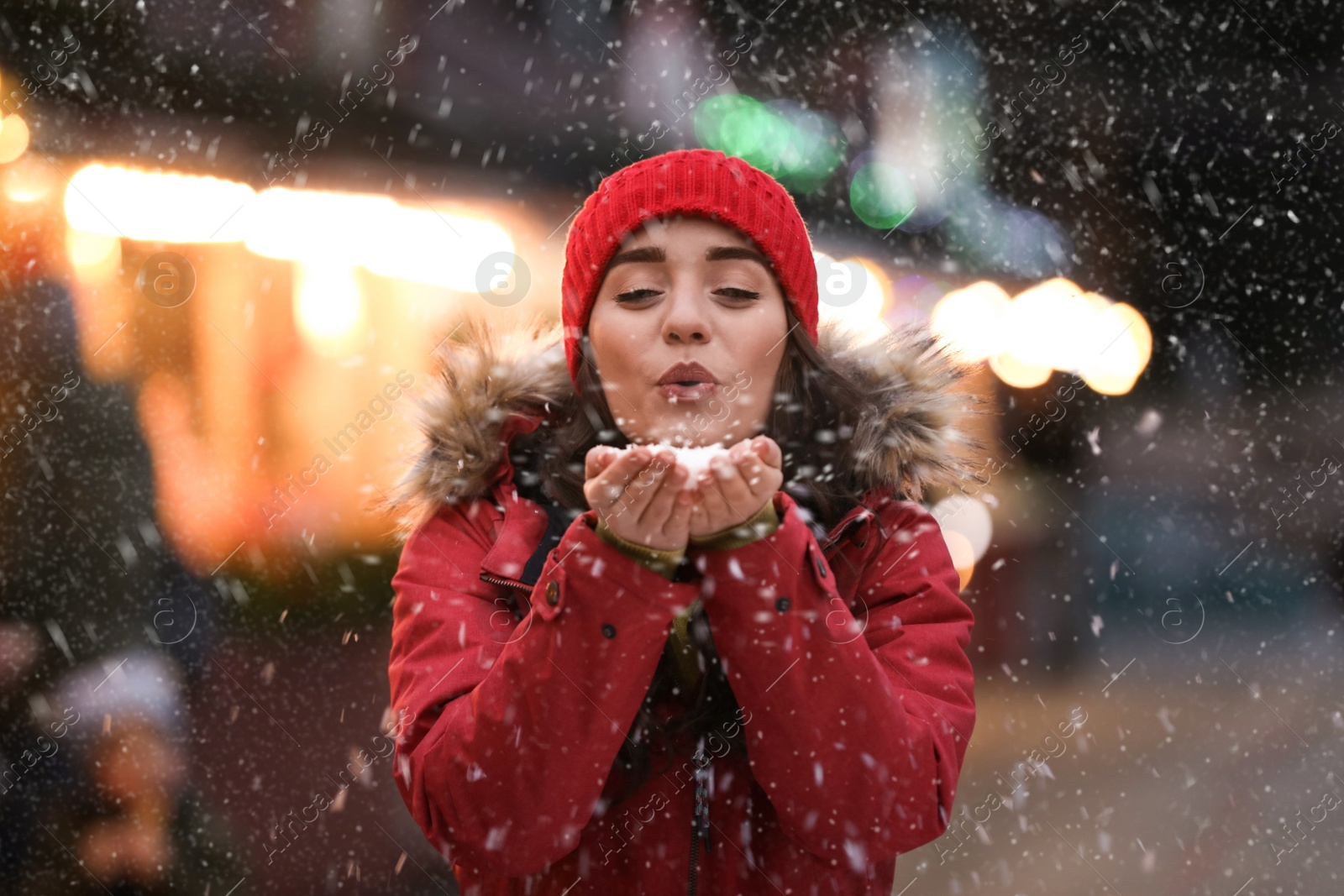 Image of Happy young woman blowing snow at winter fair. Christmas celebration
