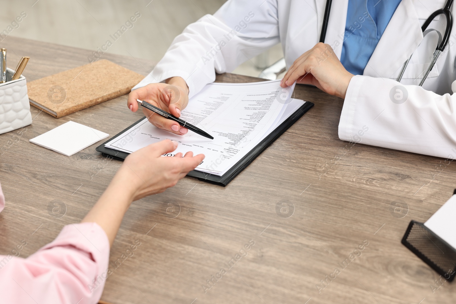 Photo of Doctor with results of laboratory test consulting pregnant patient in clinic, closeup