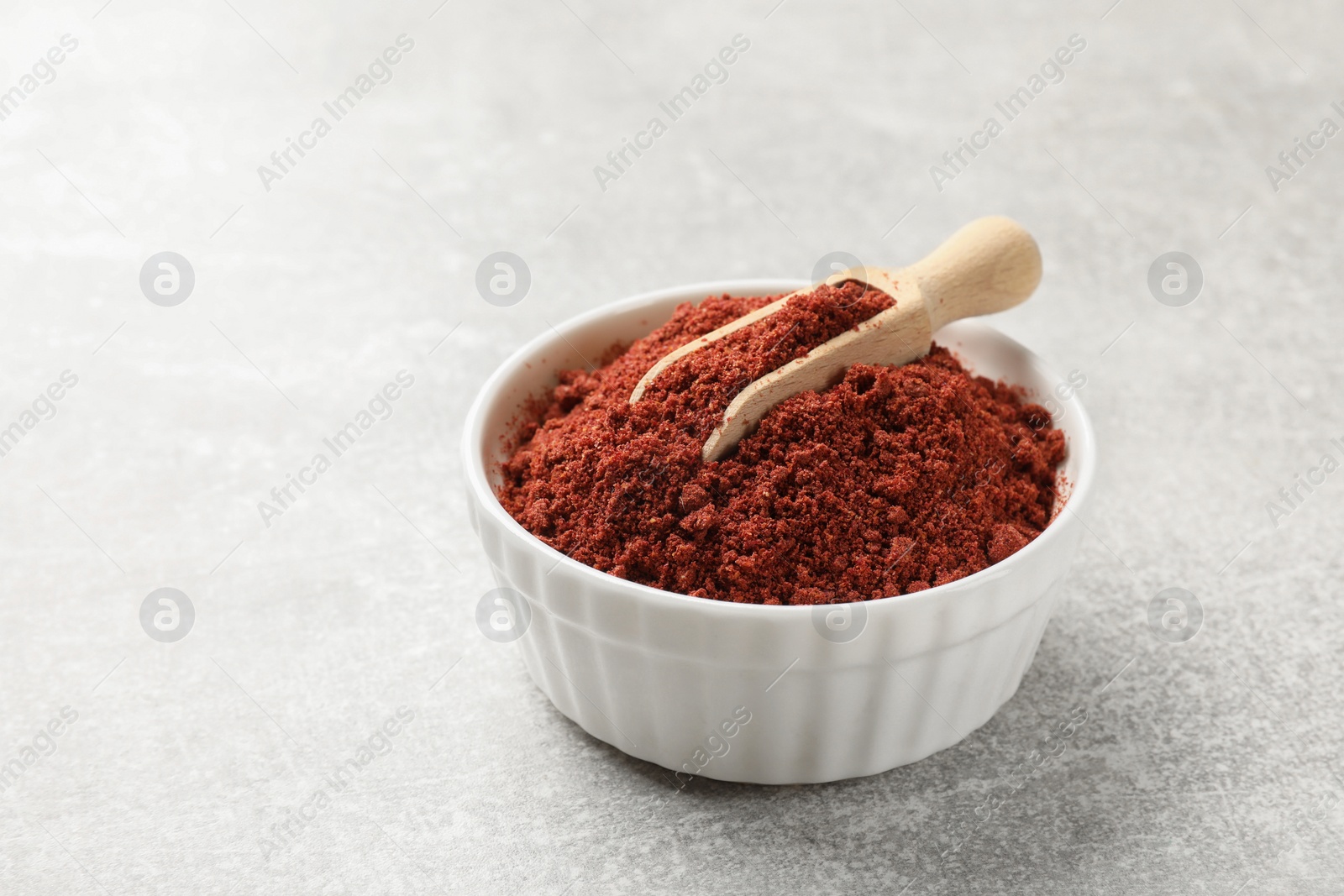 Photo of Cranberry powder in bowl and scoop on light grey table, closeup. Space for text