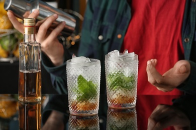 Bartender preparing delicious mint julep cocktail at table