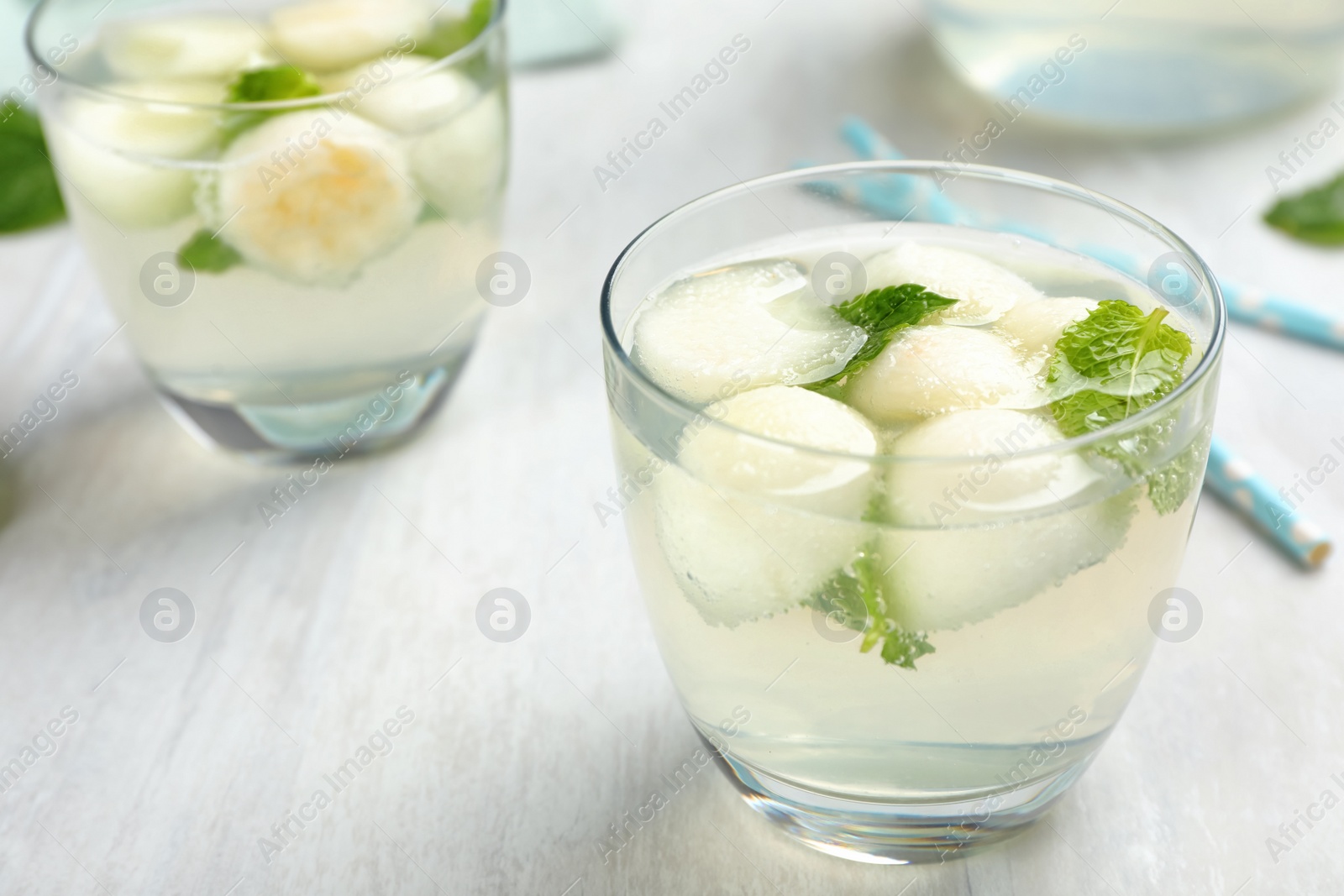 Photo of Glass with tasty melon ball drink on light table