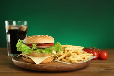 Delicious fast food menu on wooden table against green background
