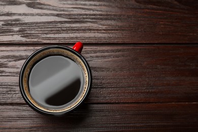 Photo of Cup of aromatic coffee on wooden table, top view. Space for text