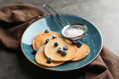 Photo of Plate with pancakes, berries and sugar powder on table