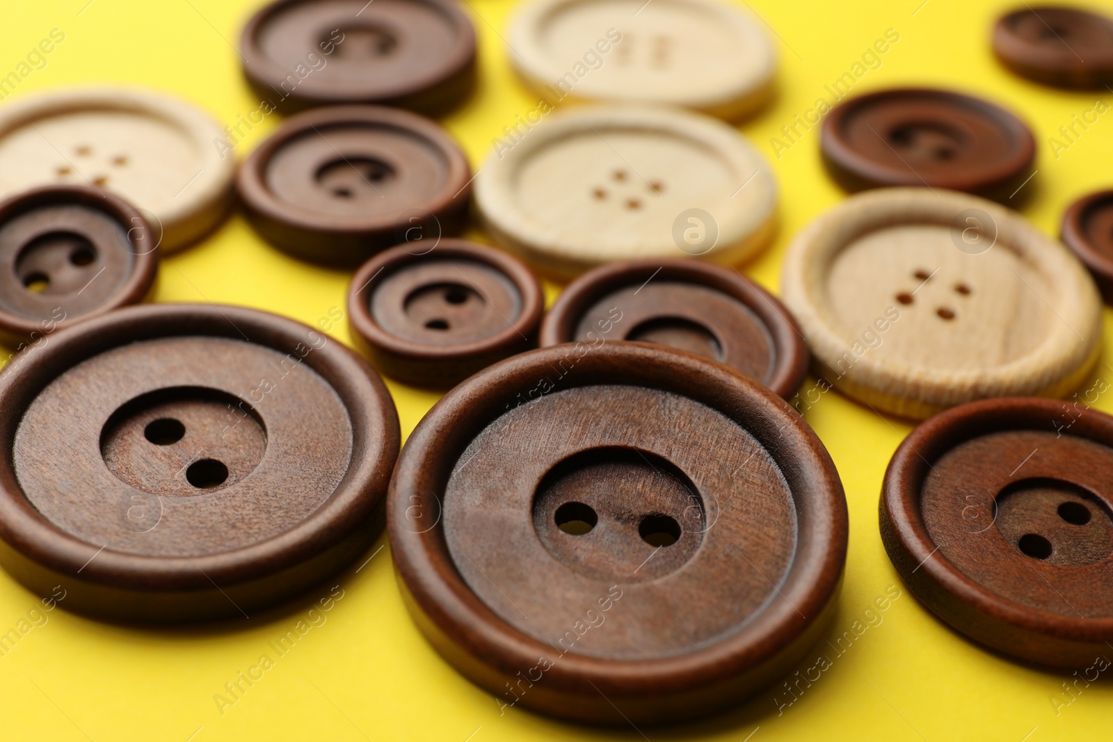 Photo of Many colorful sewing buttons on yellow background, closeup