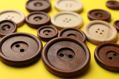 Photo of Many colorful sewing buttons on yellow background, closeup