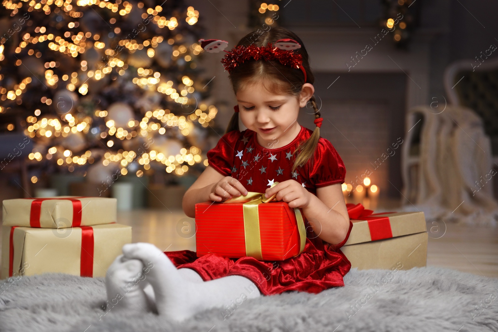 Photo of Cute little child with Christmas gift in living room