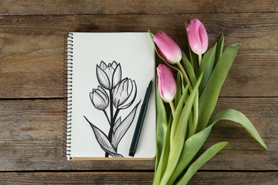 Photo of Beautiful drawing of tulips in sketchbook and flowers on wooden table, flat lay