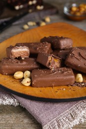 Photo of Delicious chocolate candy bars with nuts on wooden table, closeup