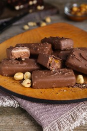 Delicious chocolate candy bars with nuts on wooden table, closeup