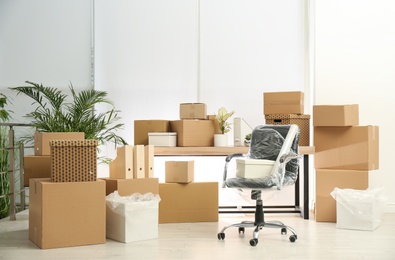 Photo of Cardboard boxes and packed chair in office. Moving day