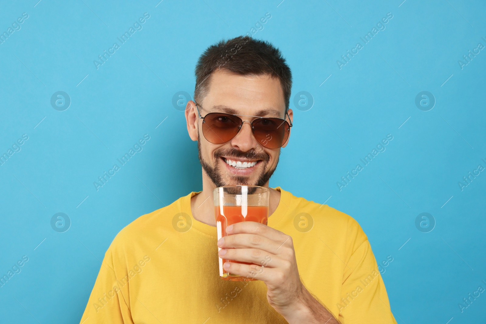 Photo of Man drinking delicious juice on light blue background