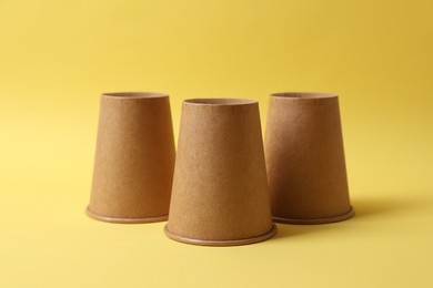 Three paper cups on yellow background. Thimblerig game