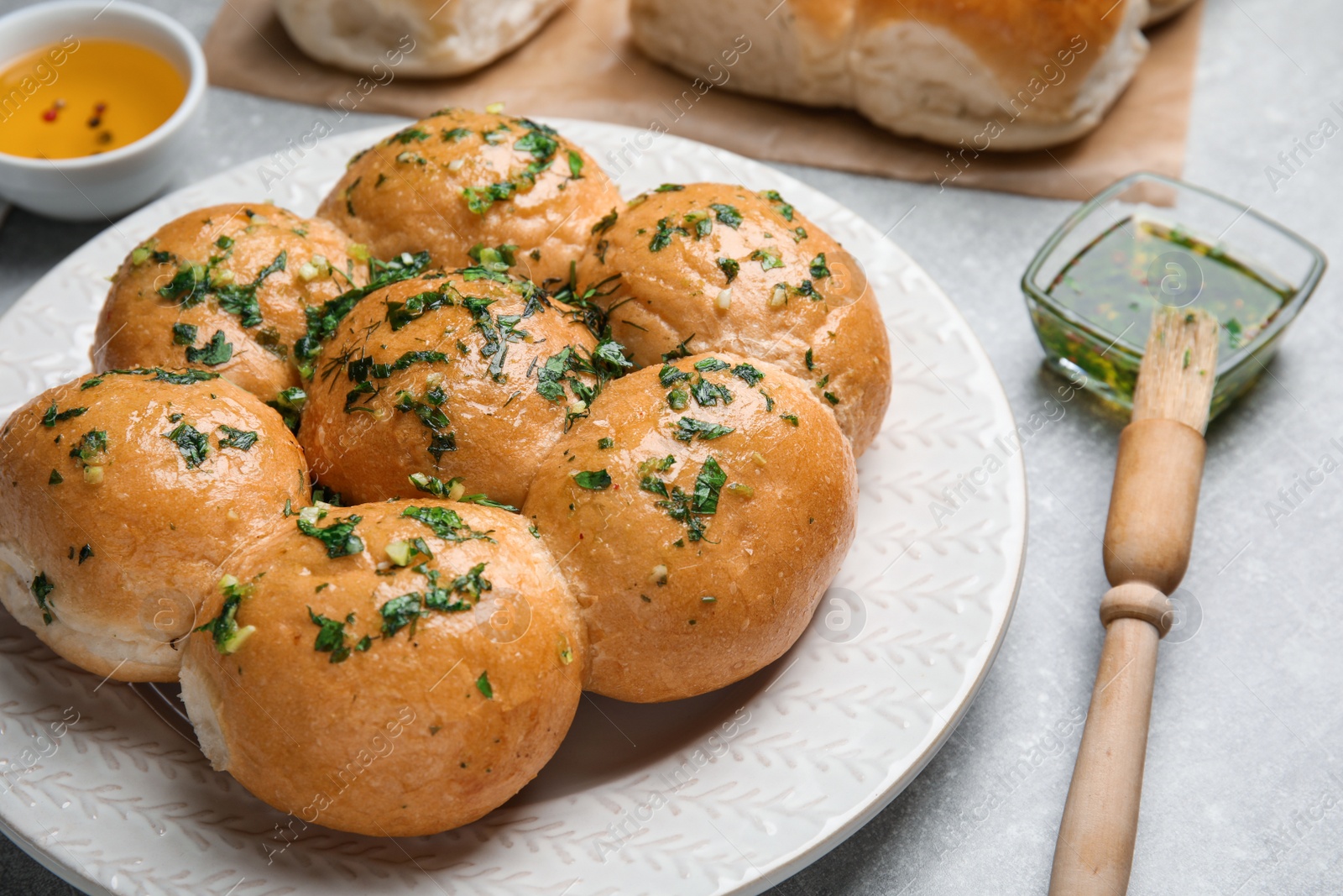 Photo of Traditional pampushka buns with garlic and herbs on grey table