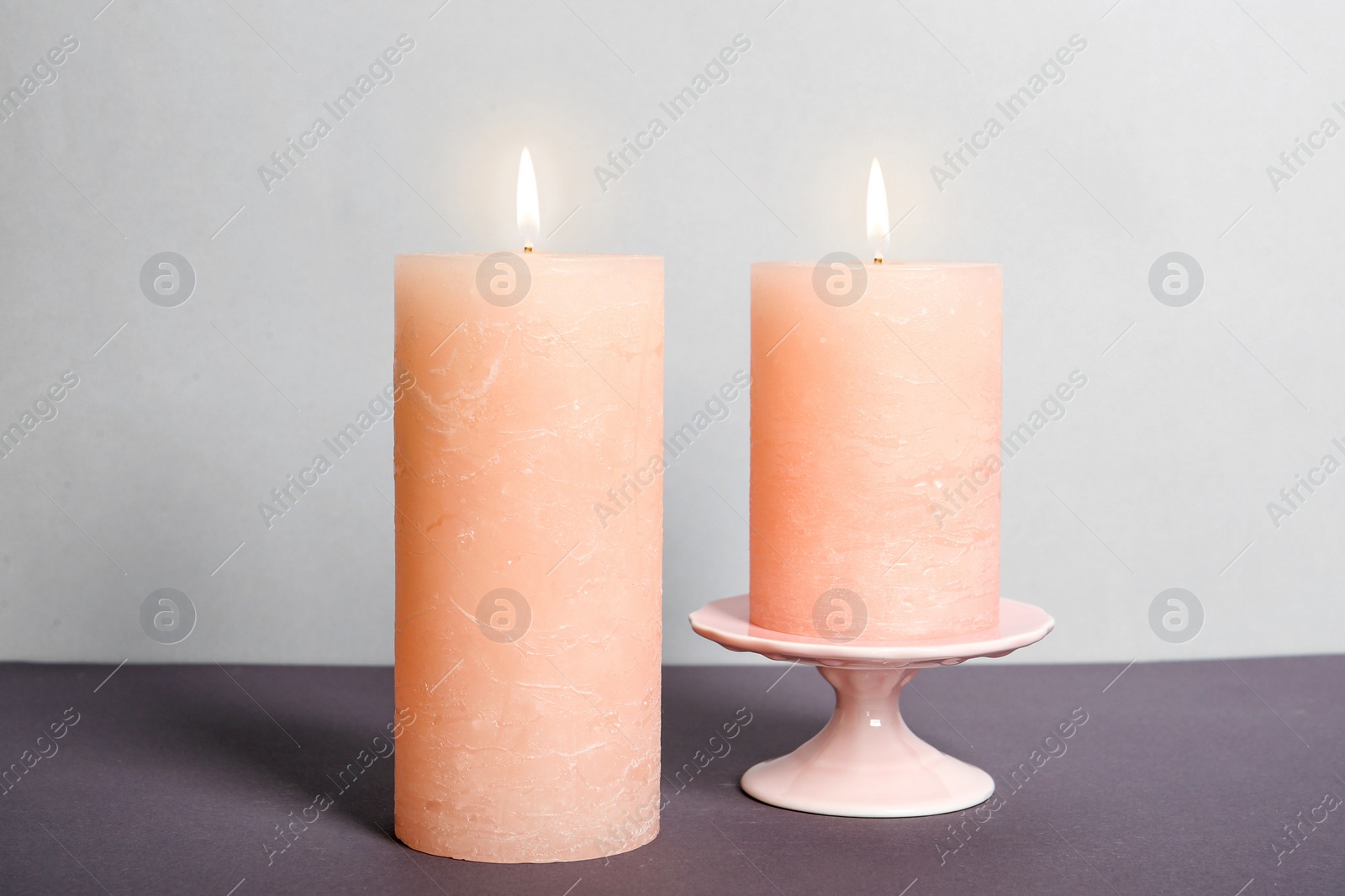 Photo of Decorative wax candles on table against light background