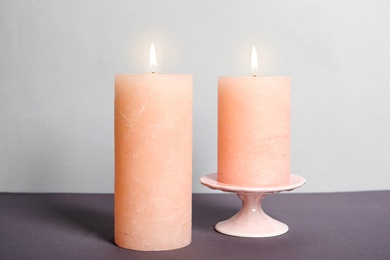 Photo of Decorative wax candles on table against light background