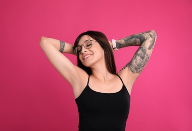 Photo of Woman with tattoos on arms against pink background
