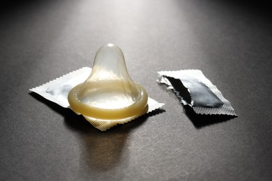 Unpacked condom and torn package on black background. Safe sex