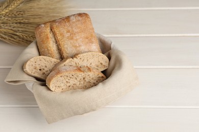 Photo of Cut delicious ciabatta in wicker basket on beige wooden table, space for text