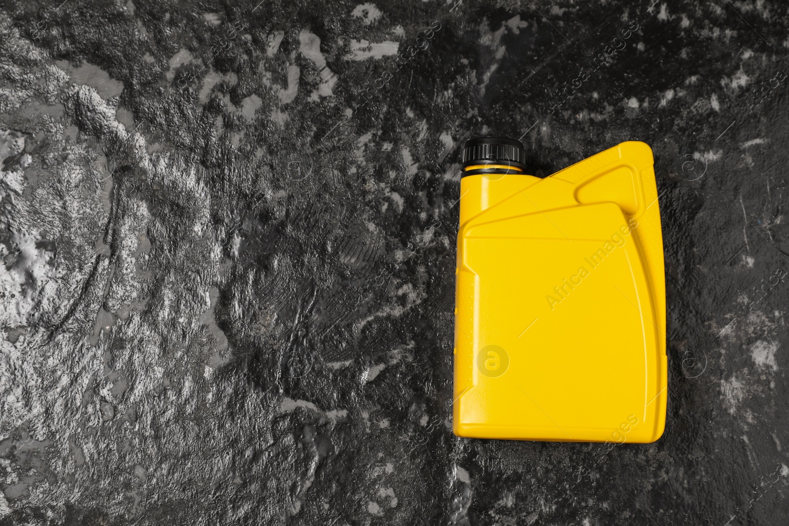 Photo of Motor oil in yellow canister on black table, top view. Space for text