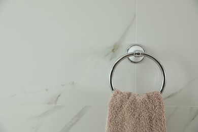 Photo of Holder with clean towel on light wall. Space for text