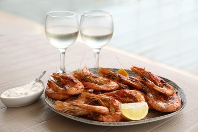 Photo of Plate of delicious cooked shrimps served with lemon and wine at table outdoors