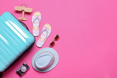 Photo of Blue suitcase and beach objects on pink background, flat lay. Space for text