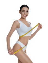 Photo of Young woman measuring waist with tape on white background