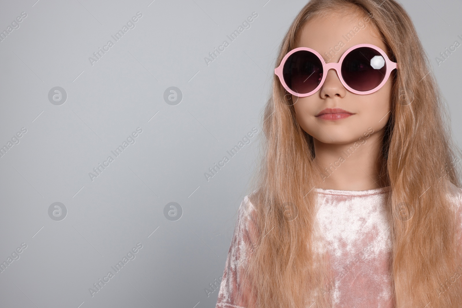 Photo of Girl in stylish sunglasses on light grey background, space for text