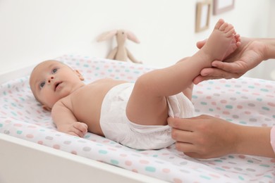 Photo of Mother changing her baby's diaper on table at home