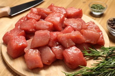 Photo of Cooking delicious goulash. Raw beef meat, rosemary and spices on wooden table, closeup