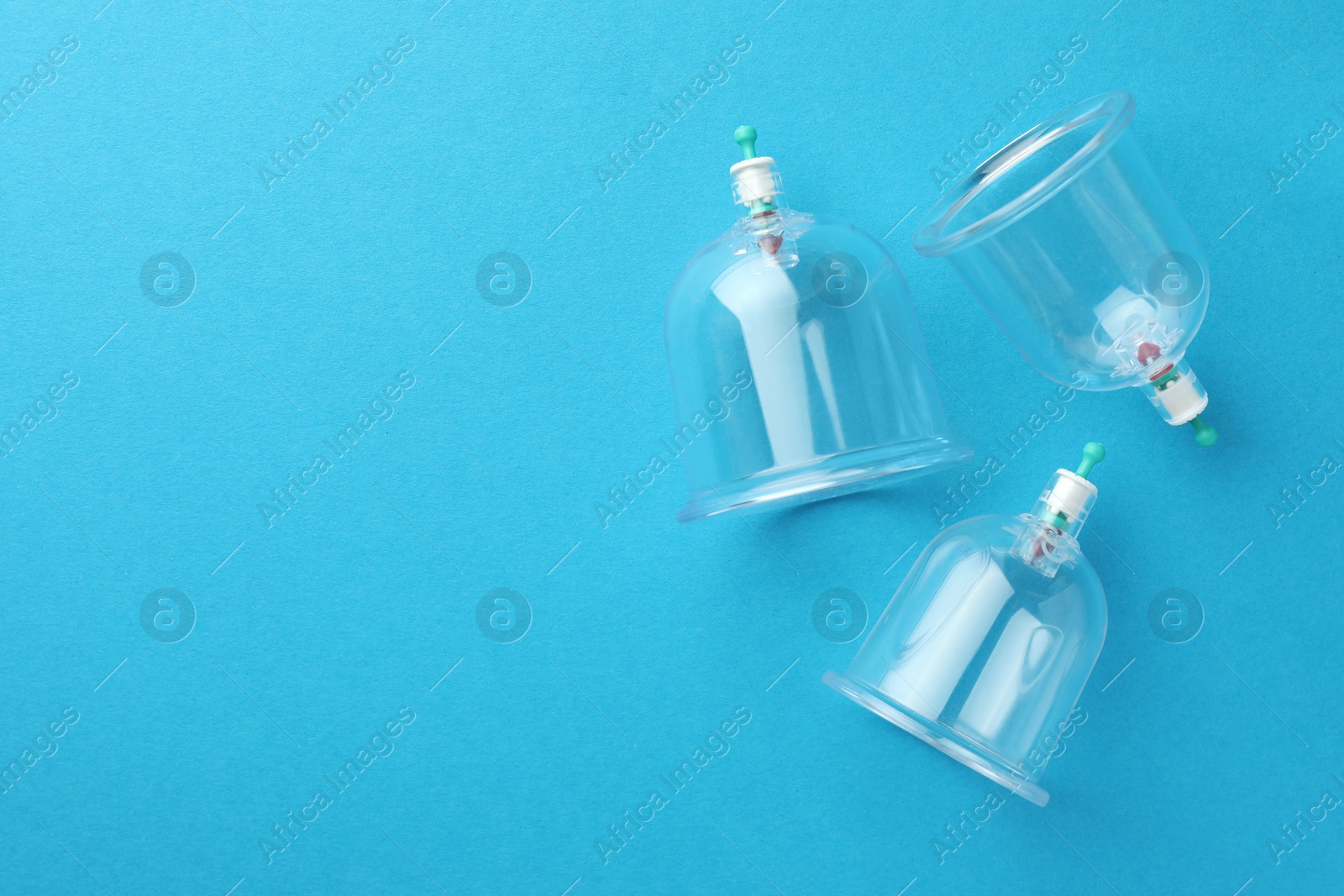 Photo of Plastic cups on light blue background, flat lay with space for text. Cupping therapy