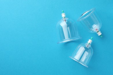 Plastic cups on light blue background, flat lay with space for text. Cupping therapy