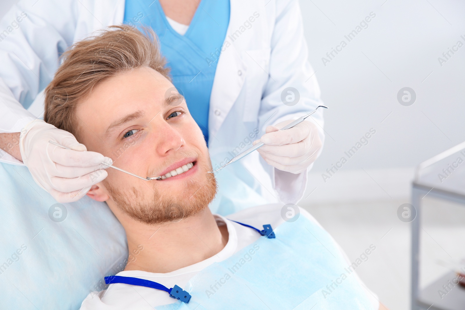 Photo of Dentist examining patient's teeth in modern clinic