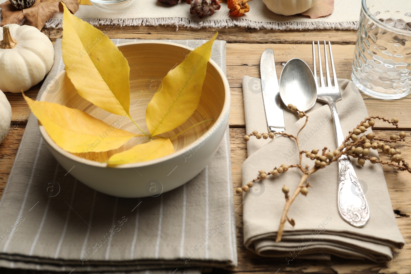 Photo of Seasonal table setting with fallen leaves and other autumn decor on wooden background