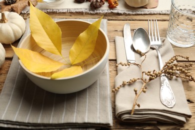 Photo of Seasonal table setting with fallen leaves and other autumn decor on wooden background